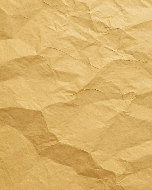 Full frame close-up of smoothed crumpled mustard yellow paper with a web of sharp creases under even lighting