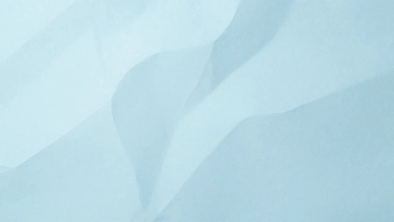 Soft crumpled pastel blue paper with gentle, diffused shadow folds across the full frame