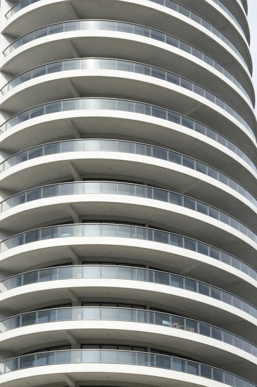 Low angle close-up of stacked curved white balconies on a modern apartment high-rise