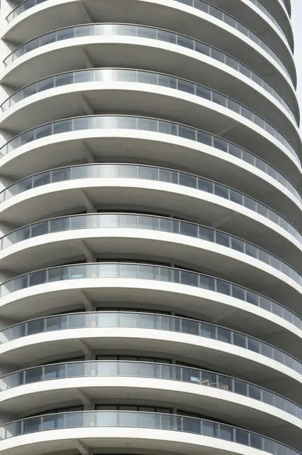 Low angle close-up of stacked curved white balconies on a modern apartment high-rise