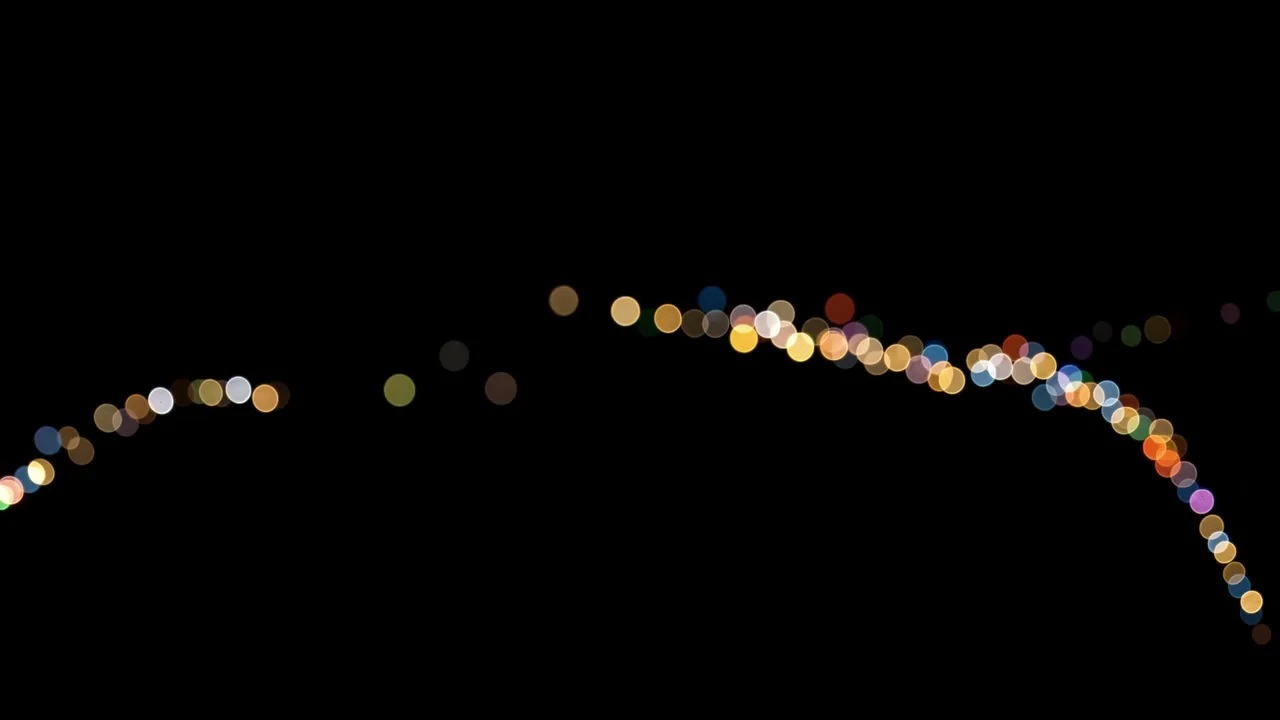 A gentle curving line of colorful soft bokeh circles rests against a pure solid black background