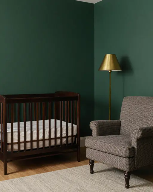A nursery room corner with deep green walls, dark wood crib, tweed armchair, and brass floor lamp