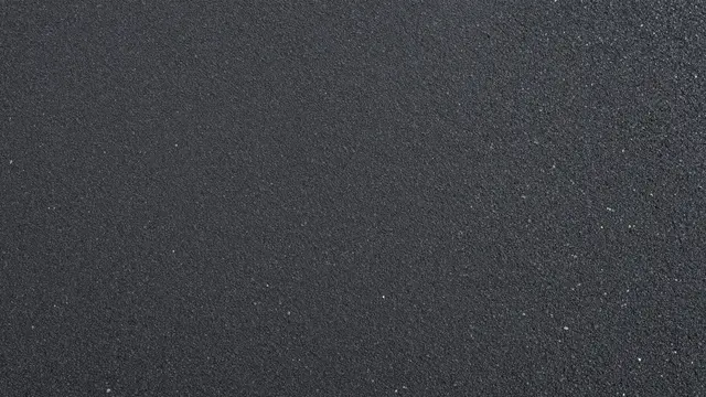 Top view of smooth dark asphalt with tiny embedded light aggregate stones under even flat lighting