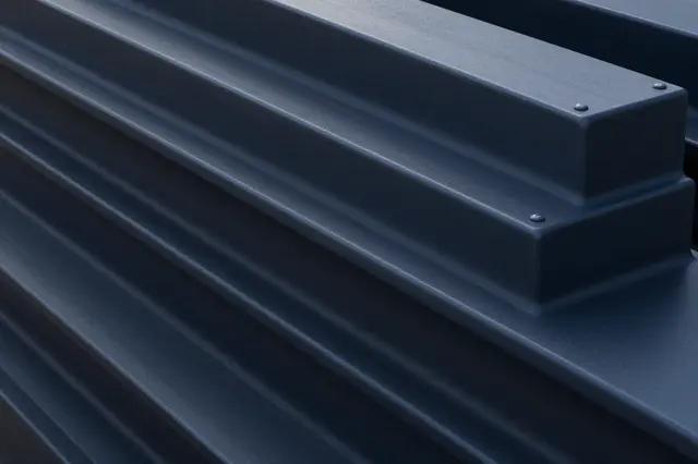 Close-up full frame view of ribbed dark blued steel with a deep blue-black sheen under soft light