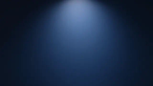 A smooth dark blue paper studio backdrop with a soft spotlight glow at the center fading to black edges