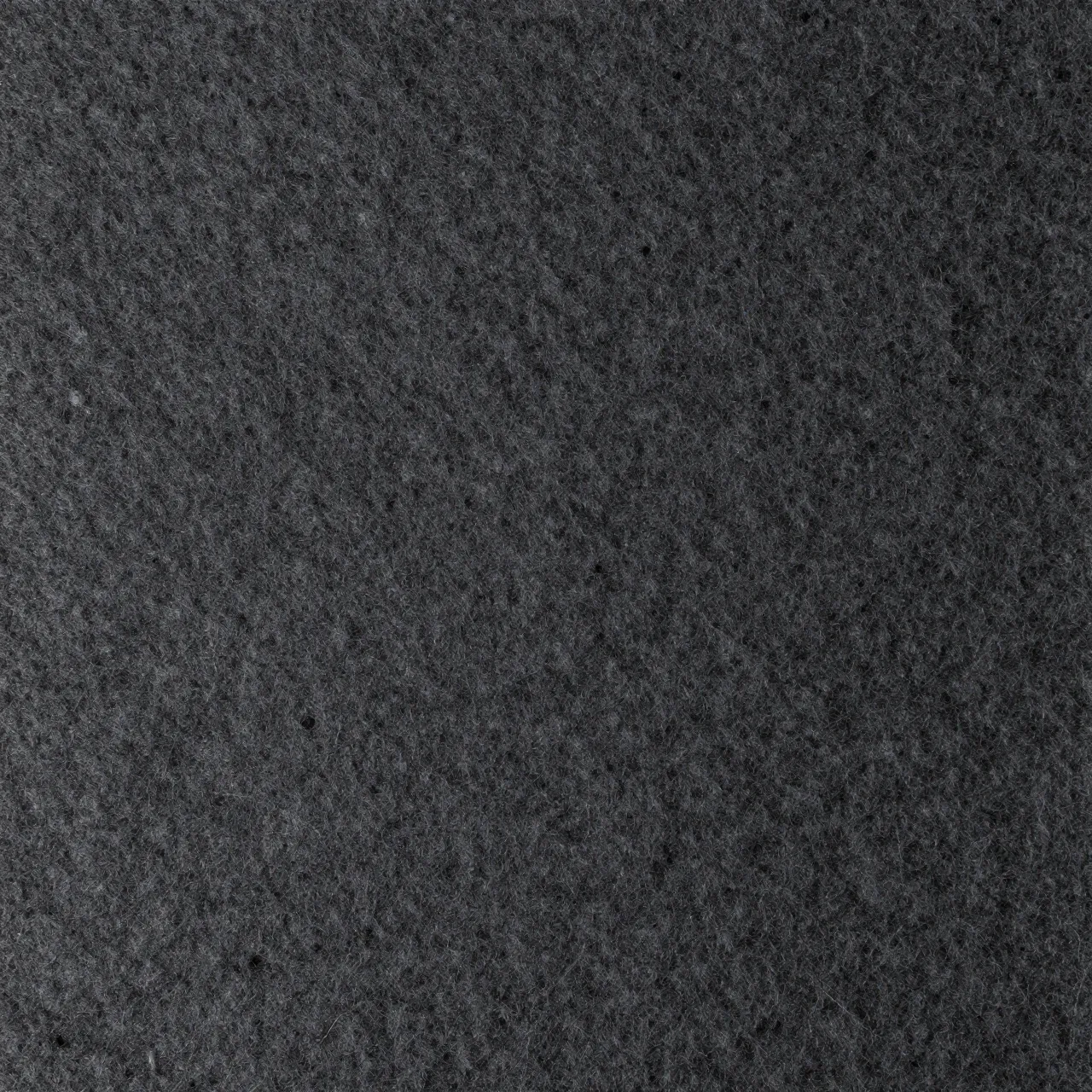 Full frame close-up of dense, compressed dark charcoal industrial felt surface