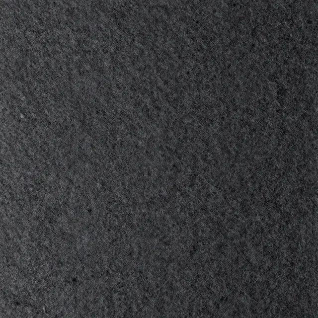 Full frame close-up of dense, compressed dark charcoal industrial felt surface