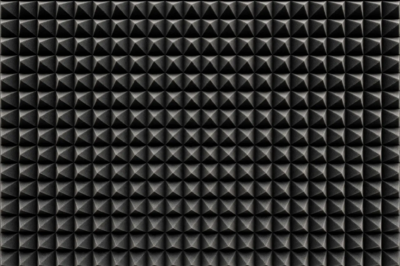 Full frame close-up of dark gray pyramid-style acoustic foam paneling with even soft lighting