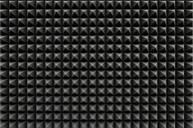 Full frame close-up of dark gray pyramid-style acoustic foam paneling with even soft lighting
