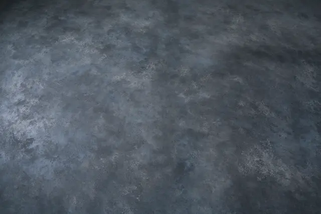 Full frame top view of a continuous low-sheen dark gray microcement surface with soft tonal shifts