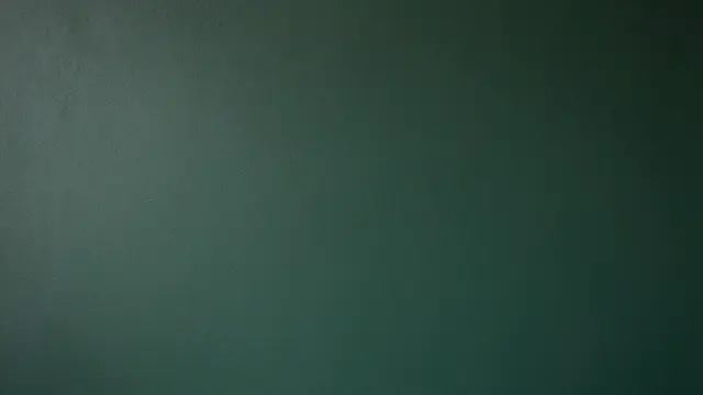 Full frame view of a textured forest green plaster wall with subtle lighting gradient