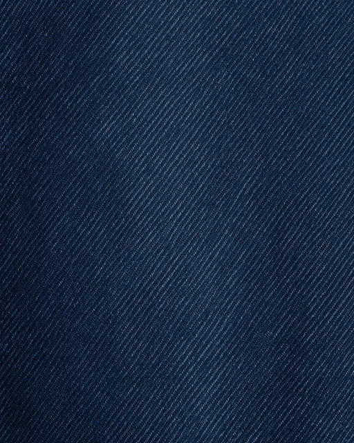 Close-up macro shot of dark indigo raw denim showing a fine diagonal twill weave pattern