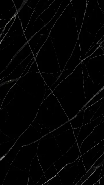Vertical full frame of black marble with thin subtle light gray veins across the surface