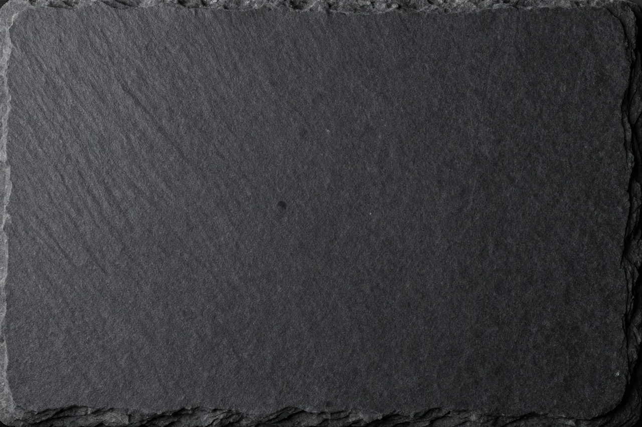 Close up top view of a rough rectangular black slate stone surface with chipped natural edges