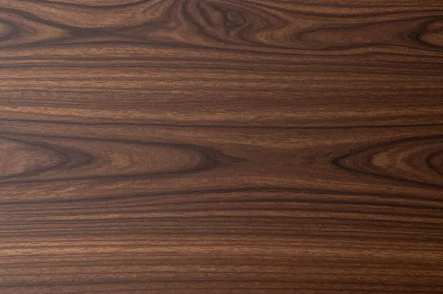 Smooth natural dark walnut wood grain texture spanning the full frame as a solid background.