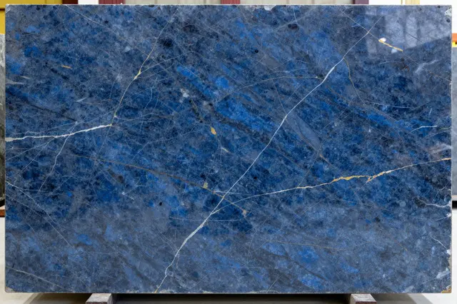 Full frame close-up of a polished deep blue marble slab with white and gold veining