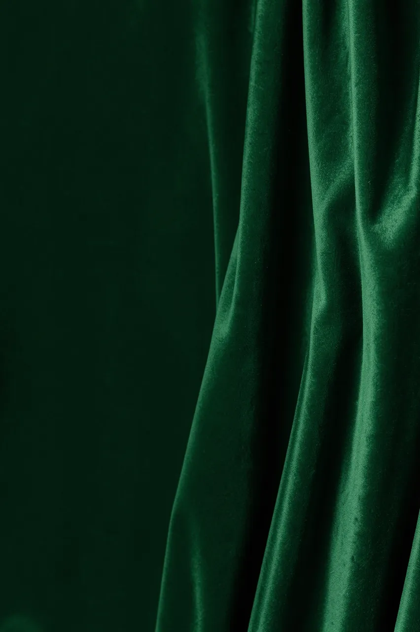 Tall background of deep green velvet fabric with soft sheen on the right and empty space on the left