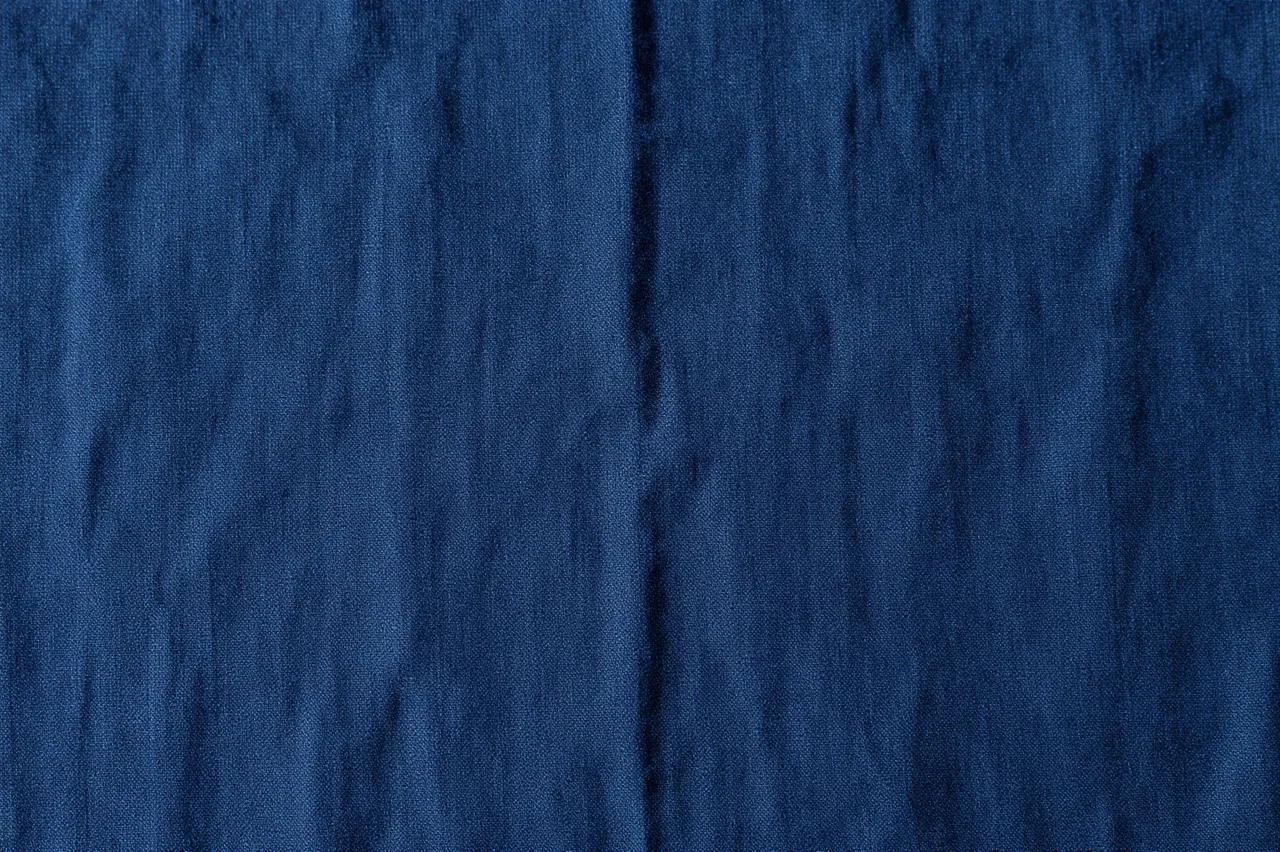 Full frame close-up of wrinkled deep indigo stonewashed linen fabric surface