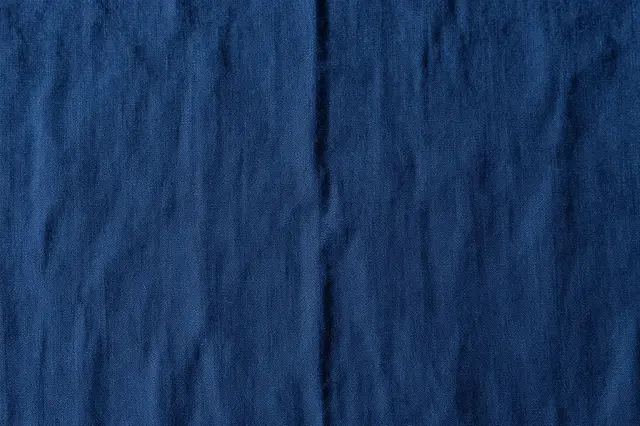 Full frame close-up of wrinkled deep indigo stonewashed linen fabric surface