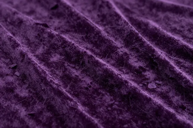 Close-up full frame view of folded deep purple crushed velvet fabric surface