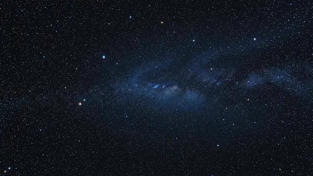 Dense starfield with a faint distant blue nebula stretches across dark cosmic space