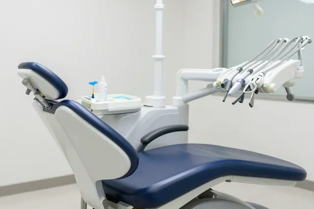Empty blue and white dental chair with mounted tools in a bright modern clinic room