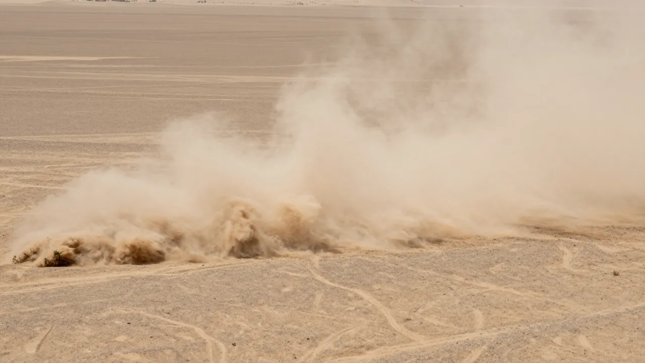 A thick churning dust storm billows across a flat arid desert plain with faint tire tracks