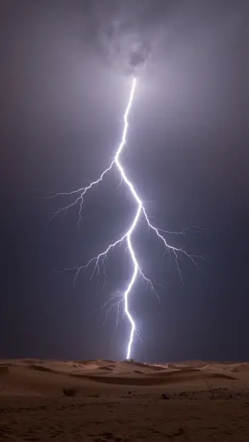 Bright forked lightning illuminates sand dunes across a dark stormy desert sky at night