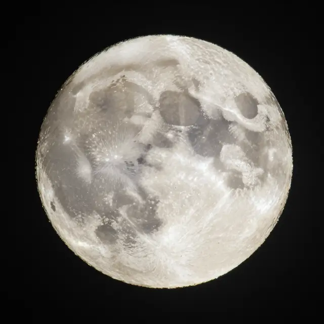 A close-up detailed view of a cratered full moon set against a solid black night sky