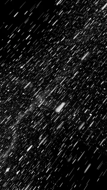 Diagonal streaks of wind-blown falling snow appear against a solid pure black background