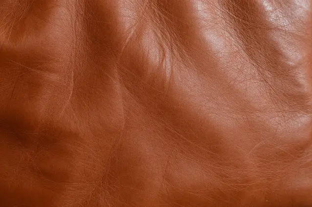 Close-up full frame of worn distressed cognac leather with natural creases and subtle sheen