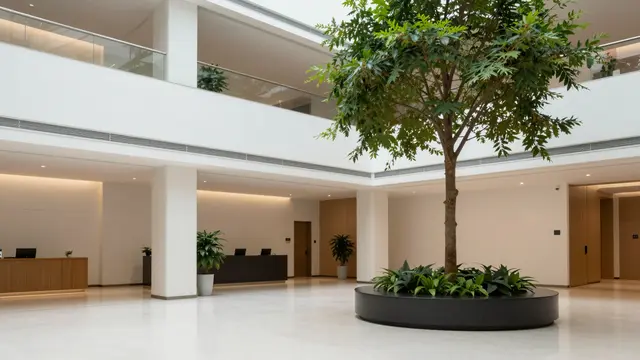 Empty modern corporate lobby atrium featuring a tall indoor tree in a circular planter