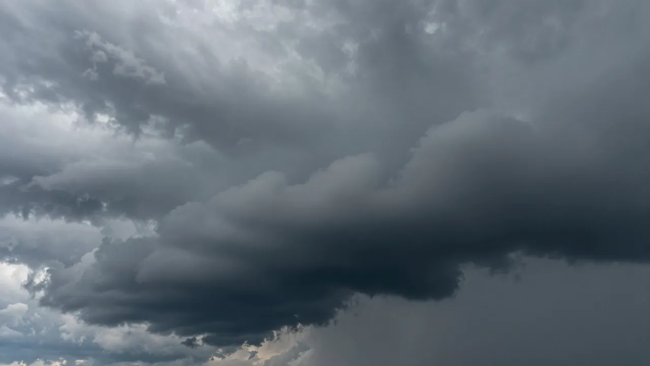 Heavy dark gray storm clouds fill a turbulent, overcast sky before rain