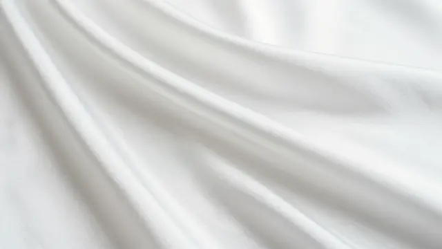 Soft flowing folds of smooth white satin fabric fill the full frame of the view