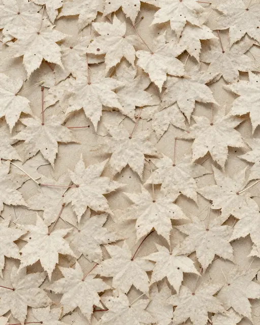 Full frame close-up of overlapping pale bleached maple leaves laid flat on a matching light neutral base.