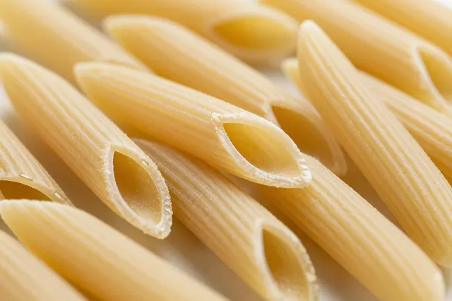 Close-up shot of uncooked ridged penne pasta filling the frame in soft natural light
