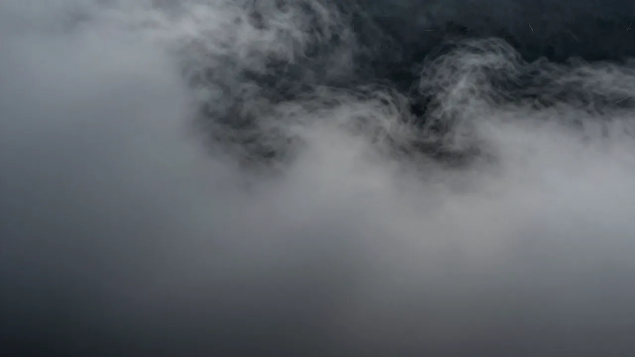 Wispy thick gray fog drifts across a deep muted dark background