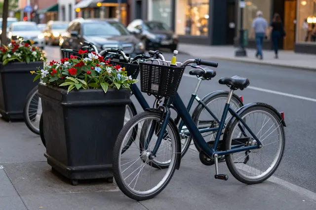 Parked bicycles next to flower planters on an urban city sidewalk at dusk