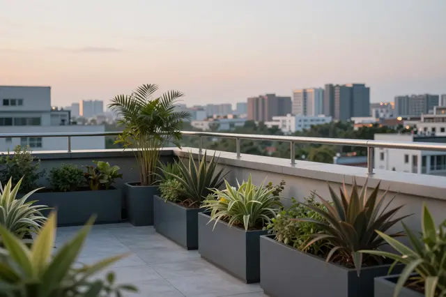 A modern rooftop terrace with potted plants overlooks a city skyline at soft dusk