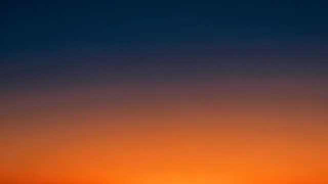 A smooth seamless gradient shifting from deep midnight blue to warm orange like a dusk sky