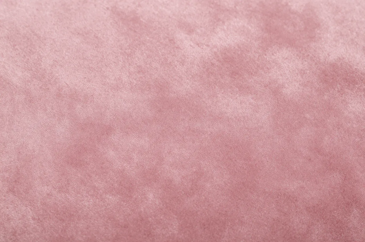 Close-up full frame view of soft muted dusty pink velvet fabric with subtle shading variations