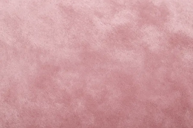 Close-up full frame view of soft muted dusty pink velvet fabric with subtle shading variations
