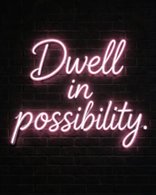 Glowing white neon sign with soft pink halo displaying "Dwell in possibility." mounted on a dark brick wall at night