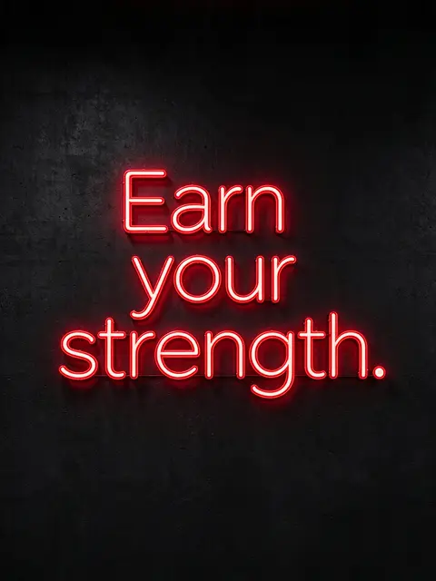 Glowing red neon sign reading "Earn your strength." mounted on a dark textured concrete wall