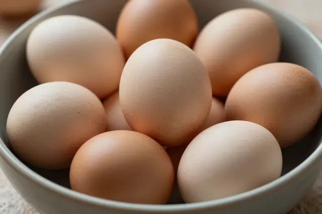 A matte ceramic bowl holds a collection of naturally dyed earth-tone Easter eggs in warm brown and beige shades.