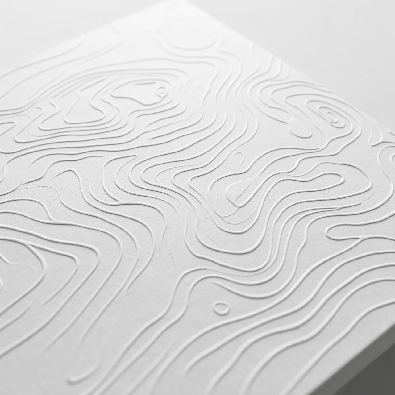 Close-up of embossed white topographic contour lines on thick textured paper with low side lighting