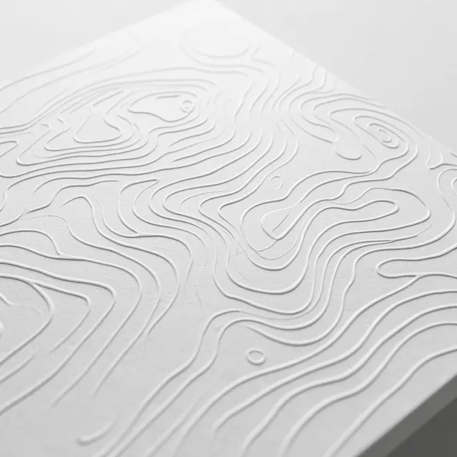 Close-up of embossed white topographic contour lines on thick textured paper with low side lighting