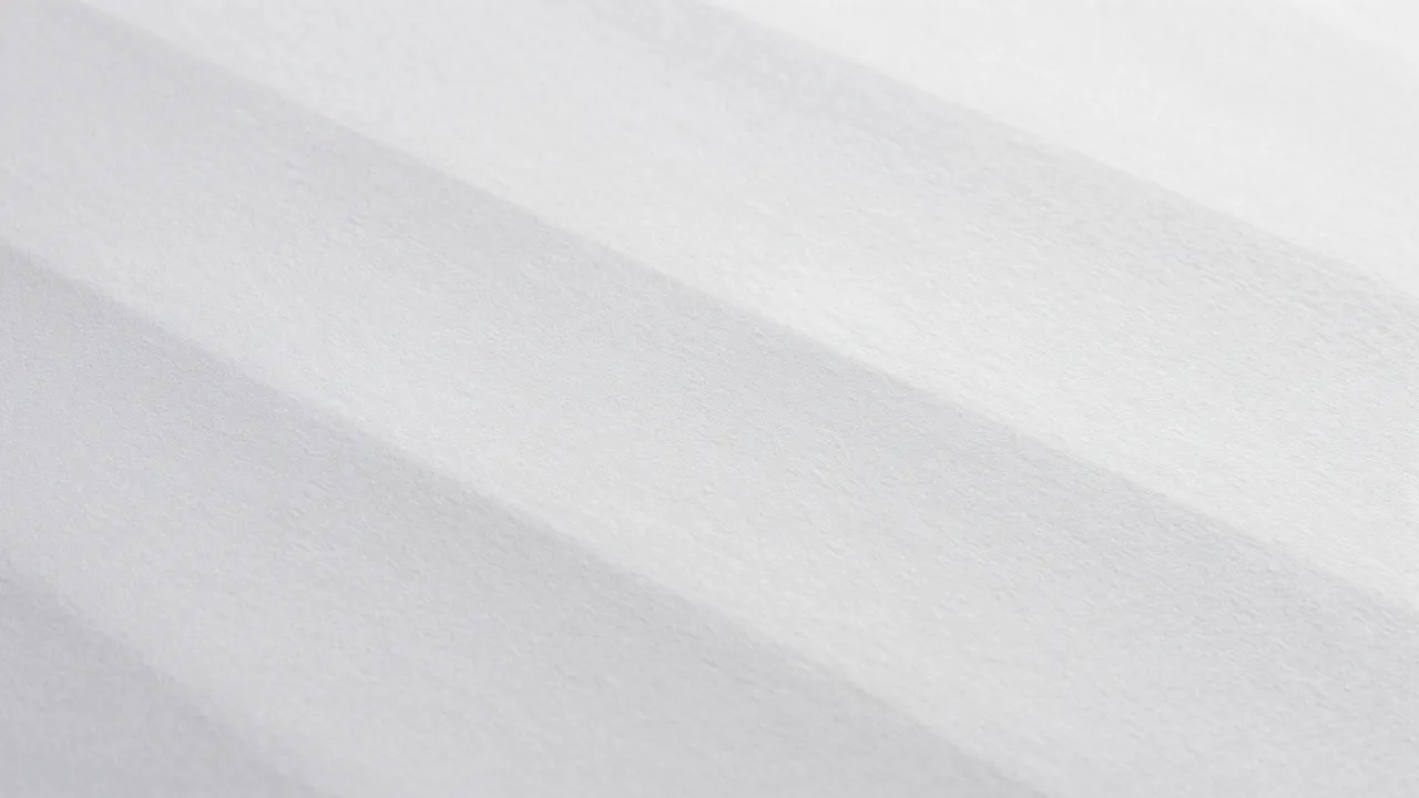 Full frame close-up of blind embossed white paper with soft raised waves lit by raking light