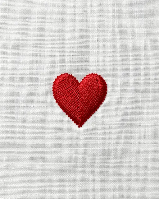 A stitched red heart centered on a plain white linen fabric background