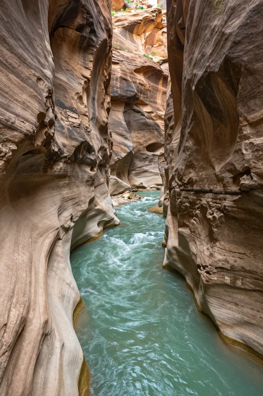 Turquoise green river flows through a narrow sculpted sandstone slot gorge